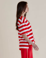 Person wearing a red and white striped shirt with red pants on a plain background