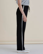 Black track pants with a white stripe worn by a person on a beige background
Evelyn Wide Leg Jogger Black