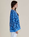 Woman wearing a blue sweater with black abstract pattern on a beige background
Palma Sweat Blue Floral