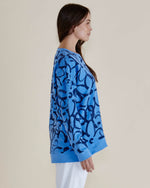 Woman wearing a blue sweater with black abstract pattern on a beige background
Palma Sweat Blue Floral