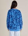 Person wearing a blue sweater with black abstract patterns on a beige background
Palma Sweat Blue Floral