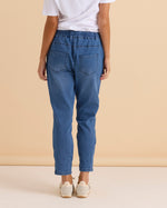 Person wearing blue jeans and a white shirt against a beige background
Brooks Jean True Blue