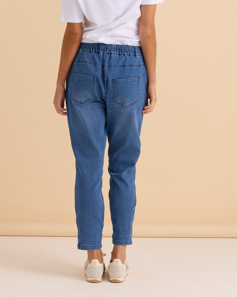 Person wearing blue jeans and a white shirt against a beige background
Brooks Jean True Blue