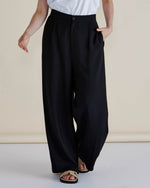 Person wearing black wide-leg pants and a white top on a plain background
Zander Pants Black
