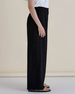 Person wearing black wide-leg pants and a white top on a beige background
Zander Pants Black