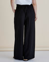 Person wearing black wide-leg pants and a white top on a beige background
Zander Pants Black