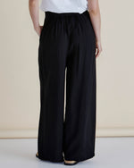 Person wearing black wide-leg pants and a white top on a beige background
Zander Pants Black
