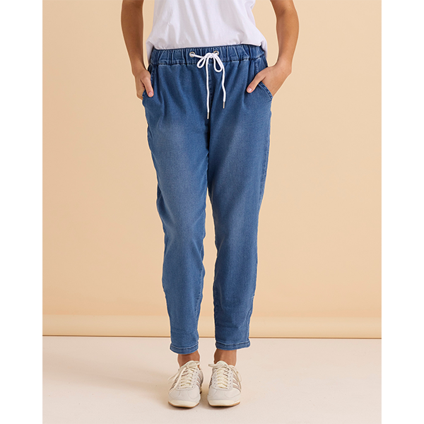 Person wearing blue jogger pants with a white top against a beige background