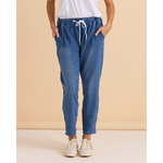 Person wearing blue jogger pants with a white top against a beige background