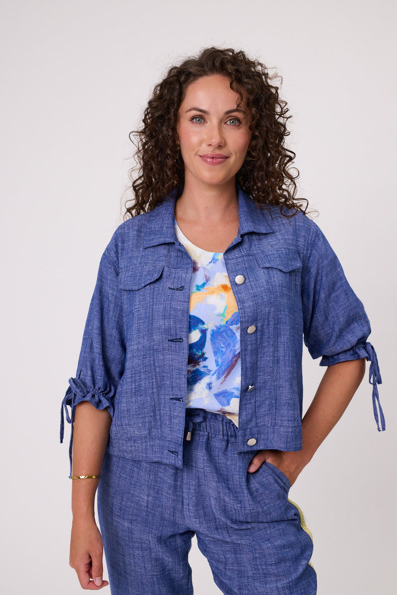 Woman wearing a blue outfit with a colorful top against a white background Venice Linen Jacket Denim
