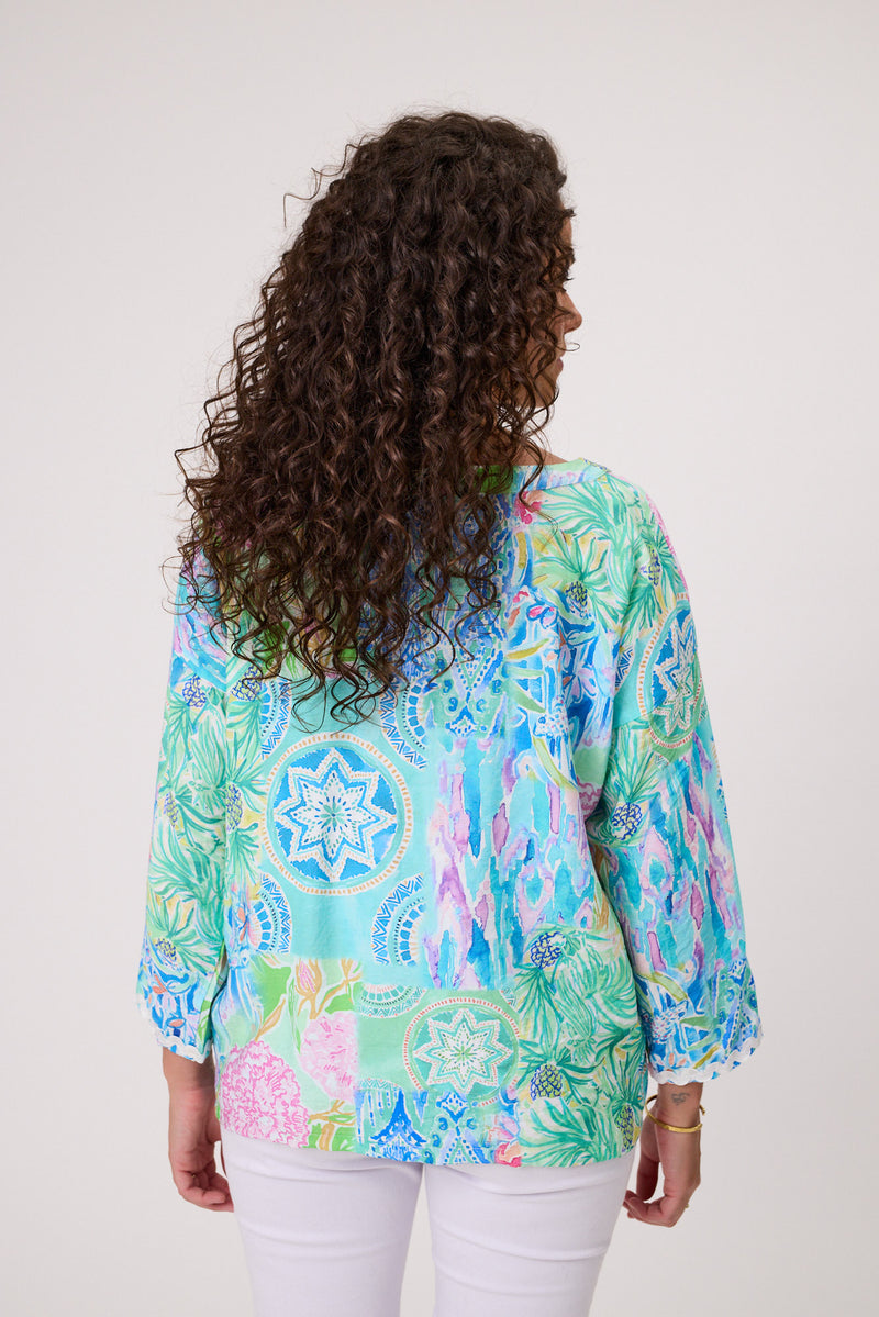 Woman wearing a colorful patterned blouse with a white background Rimini Top Aqua