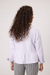 Person wearing a light purple jacket with a plain background