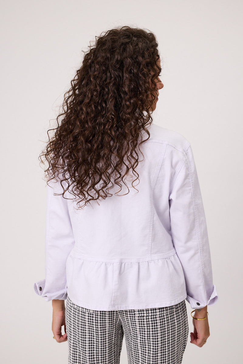 Person wearing a light purple jacket with a plain background