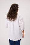 Person wearing a white shirt and blue pants with curly hair on a plain background Daisy Print Linen Top White