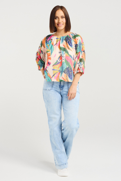 Woman wearing a colorful floral blouse and light blue jeans on a white background
Caitlin Top Vivid