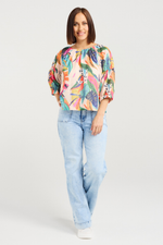 Woman wearing a colorful floral blouse and light blue jeans on a white background
Caitlin Top Vivid