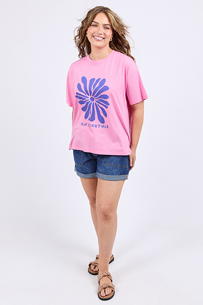 Woman wearing a pink t-shirt with a blue graphic and denim shorts on a white background
Camelia Tee Chateau Rose