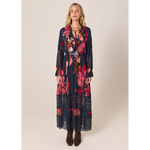 Woman wearing a long floral dress with a plain background