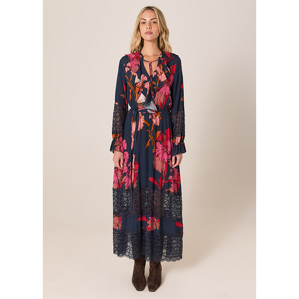 Woman wearing a long floral dress with a plain background