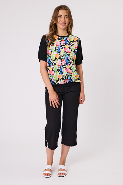 Woman wearing a black t-shirt with a colorful floral pattern and black capri pants on a white background Chloe Top Black