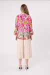 Woman wearing a colorful floral blouse and beige pants on a white background
Contessa Top Garden Print