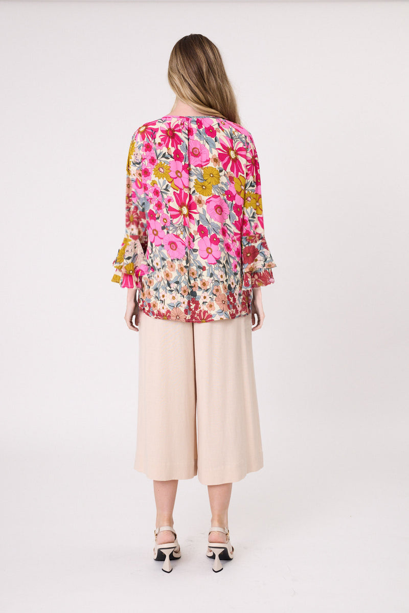 Woman wearing a colorful floral blouse and beige pants on a white background
Contessa Top Garden Print
