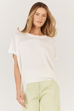 Woman wearing a white top and light green pants on a plain background Corsica knit White