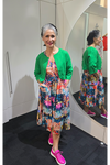 Woman in a colorful dress and green cardigan standing in front of a mirror. Crop Jacket Green