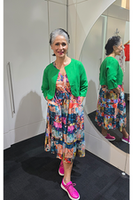 Woman in a colorful dress and green cardigan standing in front of a mirror. Crop Jacket Green