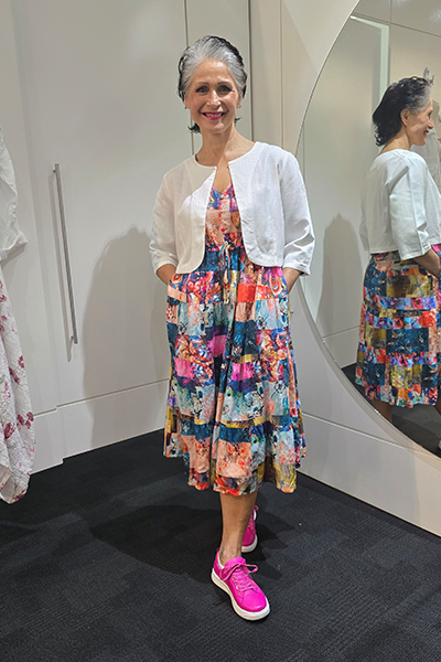 Woman in a colorful dress and white cardigan standing in front of a mirror. Crop Jacket White
