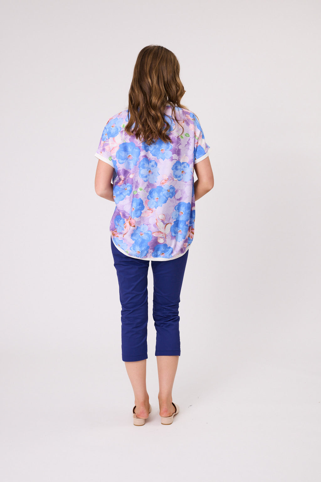 Woman wearing a colorful floral blouse and blue pants on a white background Riley Print Top Blue