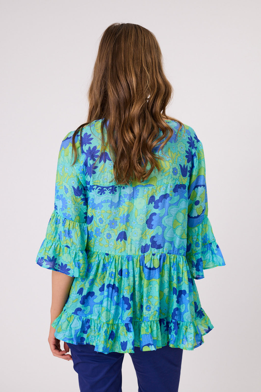 Woman wearing a blue floral blouse with ruffled sleeves on a white background Liliana Tiered Top Aqua