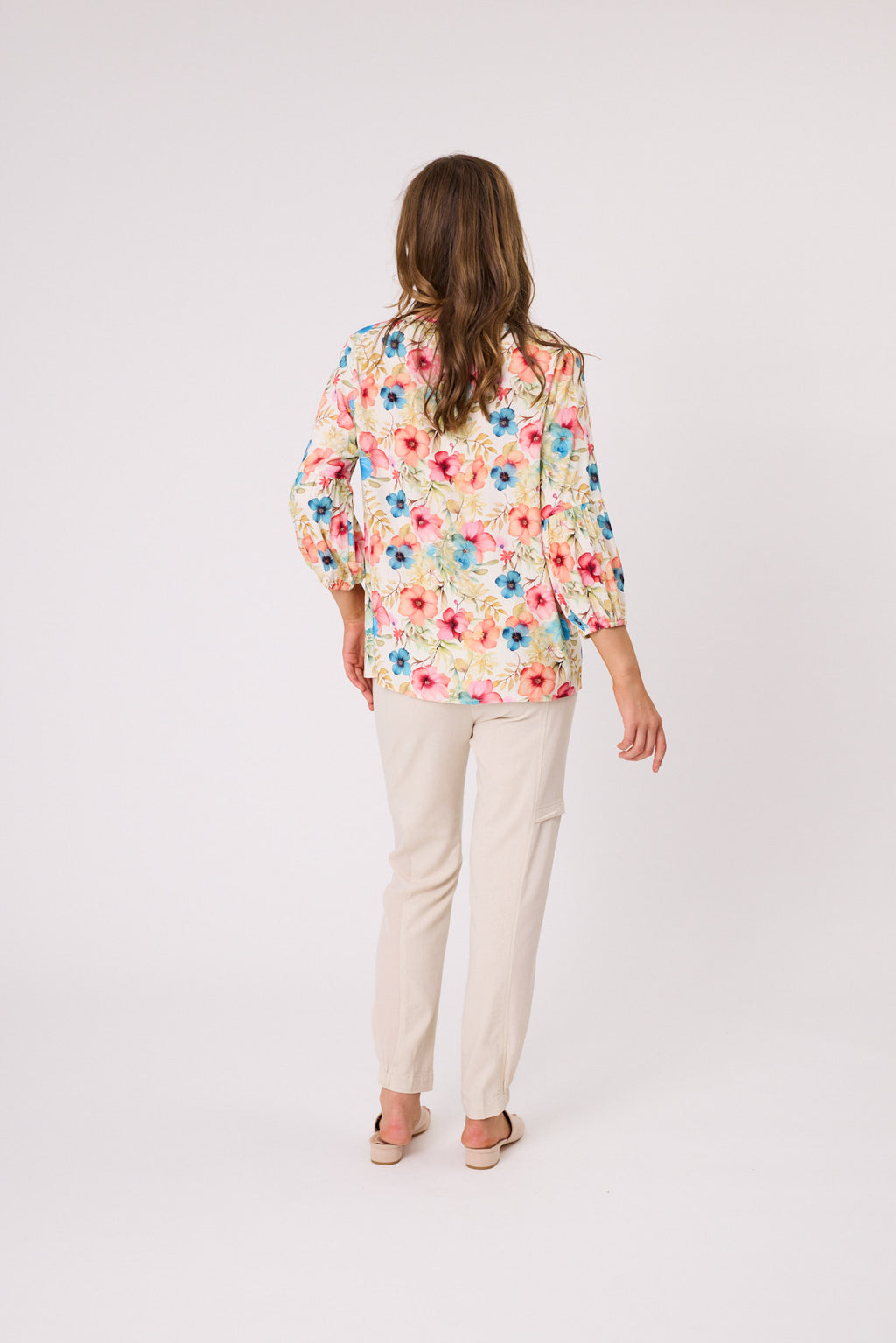 Woman wearing a floral blouse and beige pants on a white background Calli Top Pink
