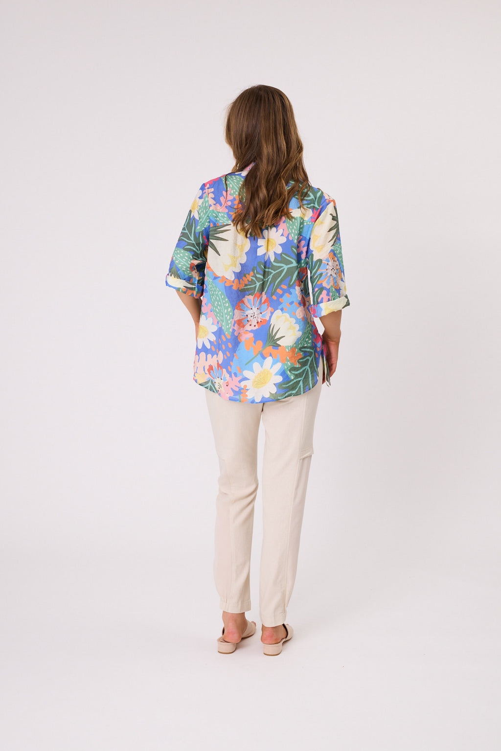 Woman wearing a colorful floral blouse and beige pants on a white background Sofia Printed Shirt Blue