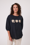Woman wearing a black blouse with floral designs on a white background Daisy Print Linen Top Black