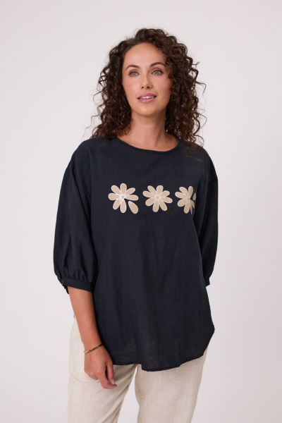 Woman wearing a black blouse with floral designs on a white background Daisy Print Linen Top Black
