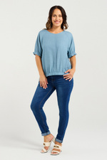 Woman wearing a blue top and jeans on a white background
Ella Top Blue