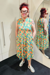 Person wearing a colorful floral dress standing in front of a mirror.
Everly Dress Green