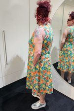 Person wearing a colorful floral dress standing in front of a mirror.
Everly Dress Green