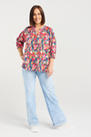 Woman wearing a colorful floral blouse and light blue jeans on a white background Evie Shirt Canvas Bloom