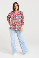 Woman wearing a colorful floral blouse and light blue jeans on a white background Evie Shirt Canvas Bloom
