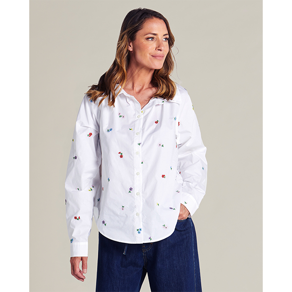 Woman wearing a white shirt with colorful patterns and blue jeans against a plain background
Floral Embroidered Shirt Blue