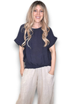 Woman wearing a navy blue top and light-colored pants on a white background Split Back River Tee Navy