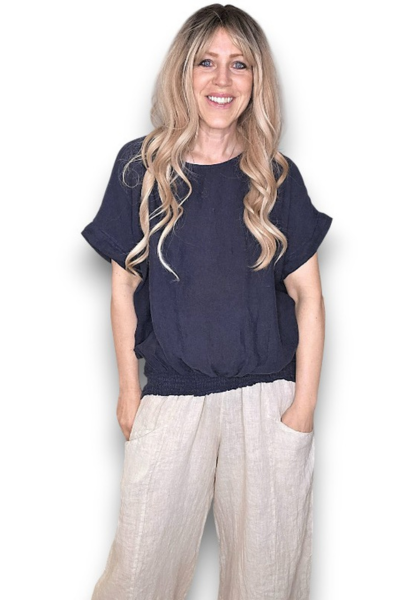 Woman wearing a navy blue top and light-colored pants on a white background Split Back River Tee Navy