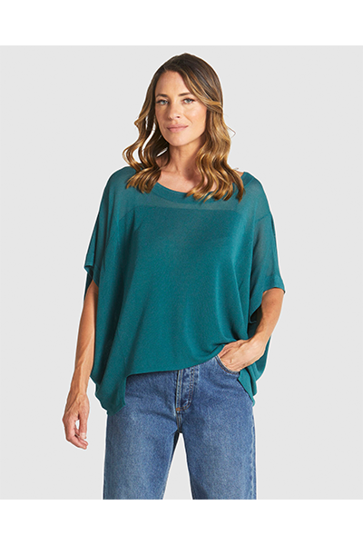 Woman wearing a teal oversized shirt and blue jeans on a white background
Irises Knit Teal
