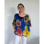 Woman wearing a colorful floral blouse against a plain background