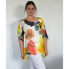 Woman wearing a colorful floral top against a plain background