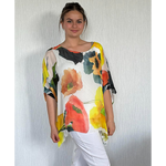 Woman wearing a colorful floral top against a plain background