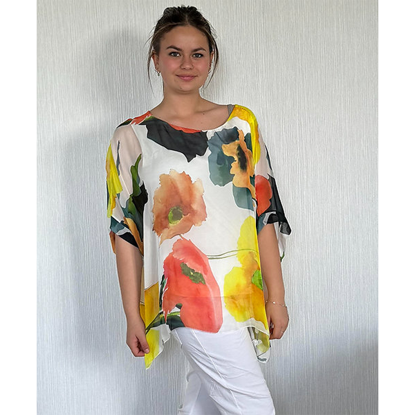 Woman wearing a colorful floral top against a plain background