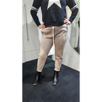 Person wearing a navy sweater with white star design and beige pants with mesh panels in a bathroom.